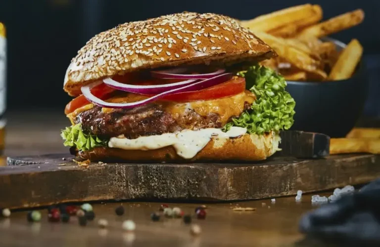 Saftiger Cheeseburger mit Pommes auf Holzbrett serviert.