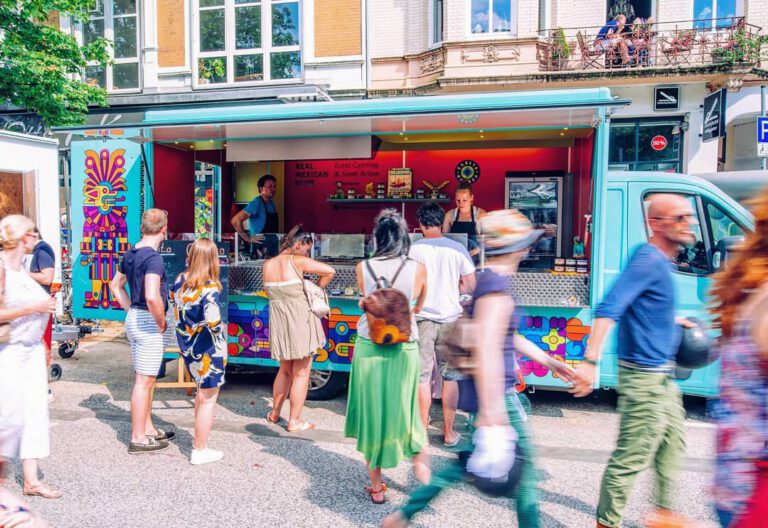Menschen stehen an einem farbenfrohen Food-Truck an.